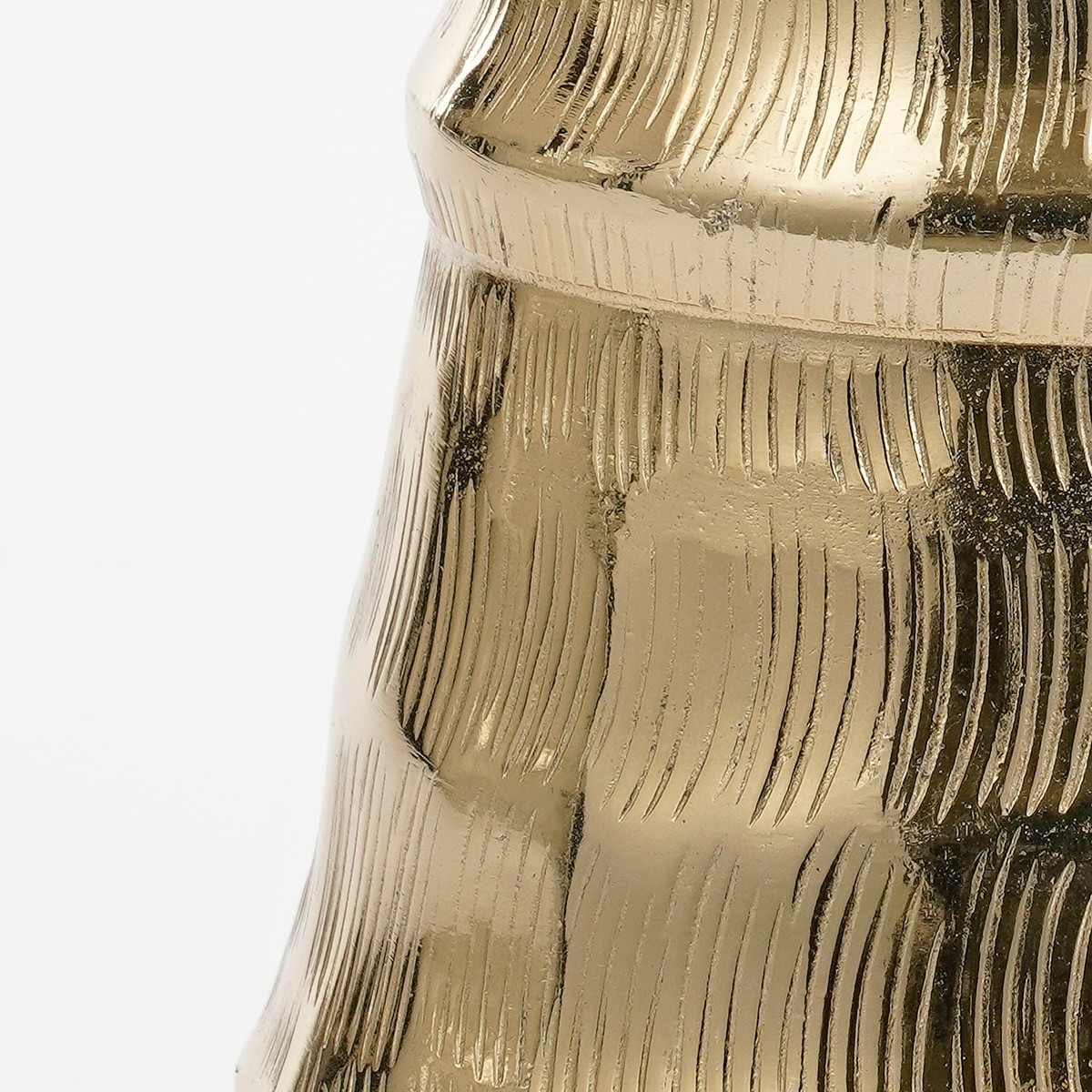 A shiny gold-colored metal object featuring textured vertical lines against a plain white background.