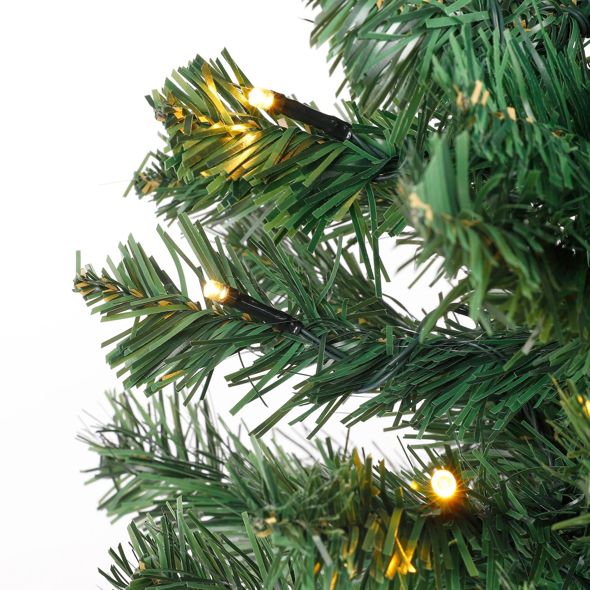 Green artificial Christmas tree branches with warm white fairy lights.
