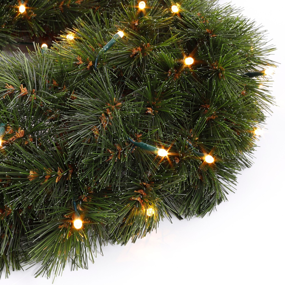 A green, snow-dusted Christmas garland with warm string lights on a white background.