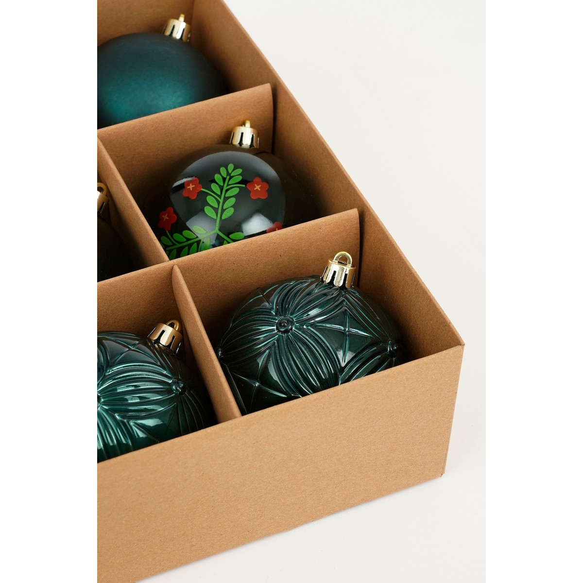 Green Christmas ornaments with various patterns are neatly arranged in a cardboard box.