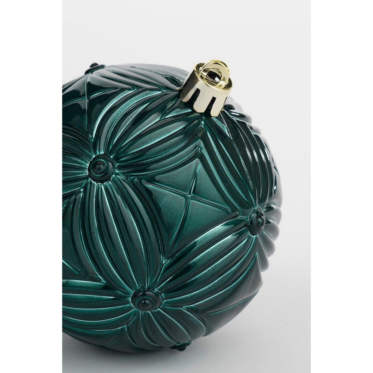 A dark green Christmas bauble with an embossed geometric pattern and a gold cap against a light background.