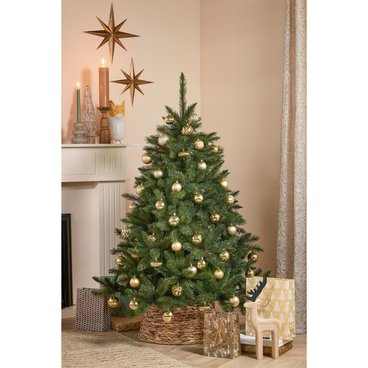 A decorated Christmas tree in a basket stands in front of a fireplace with gifts.