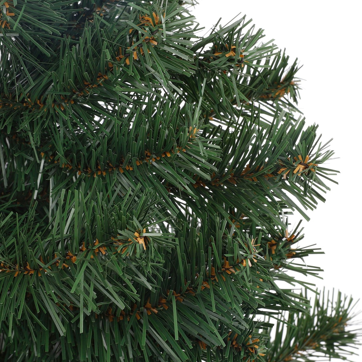 Close-up of dense green branches of an artificial Christmas tree against a white background.