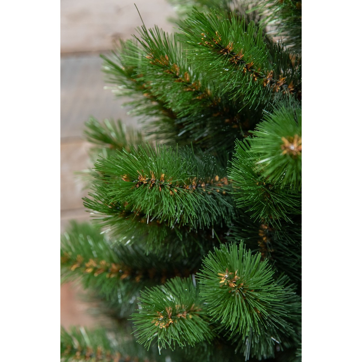 Close-up of green artificial pine branches with brown stems against a blurred background.