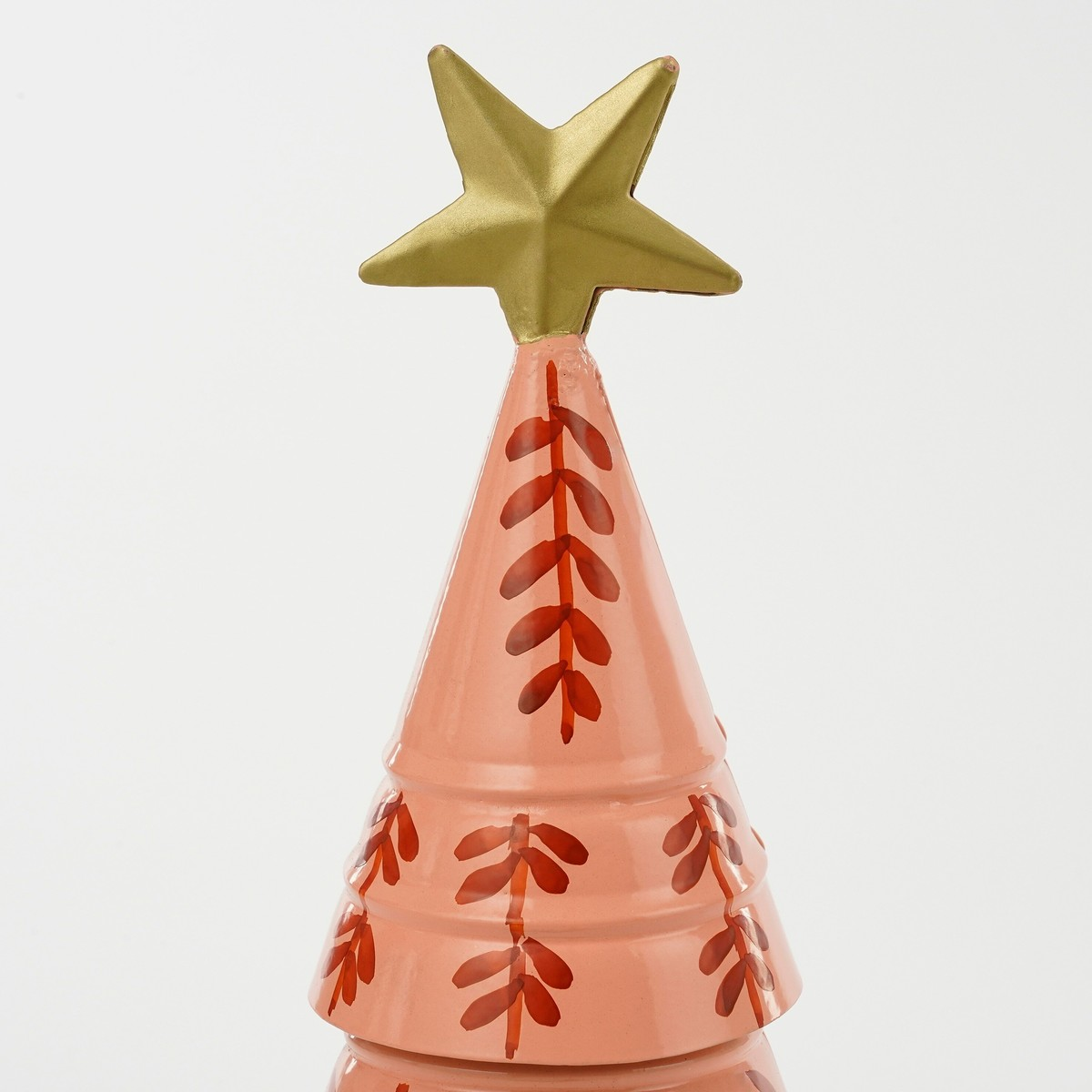 A pink metal Christmas tree featuring red leaves and topped with a gold star against a plain background.