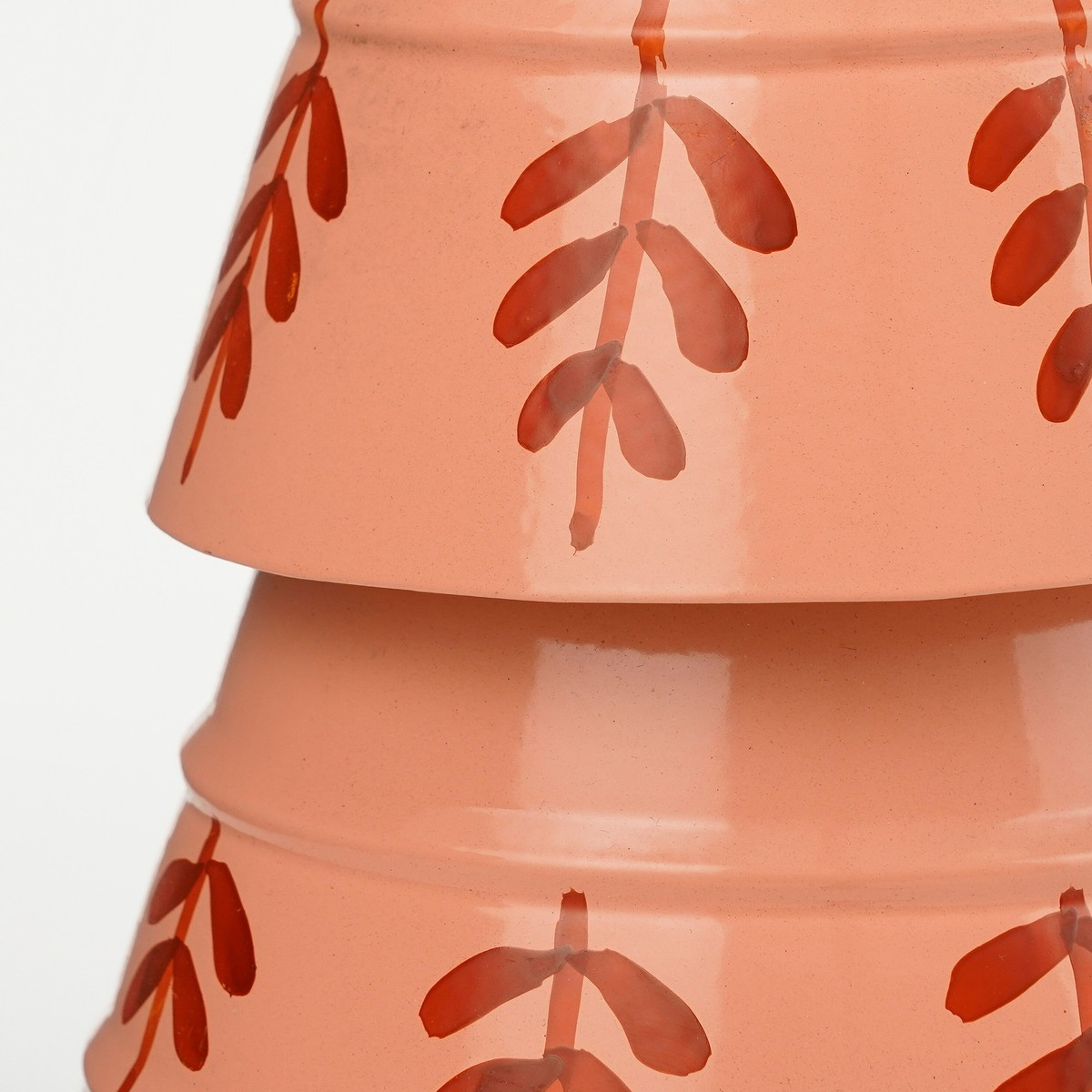 Stackable pink bowls featuring a red leaf pattern against a plain white background.
