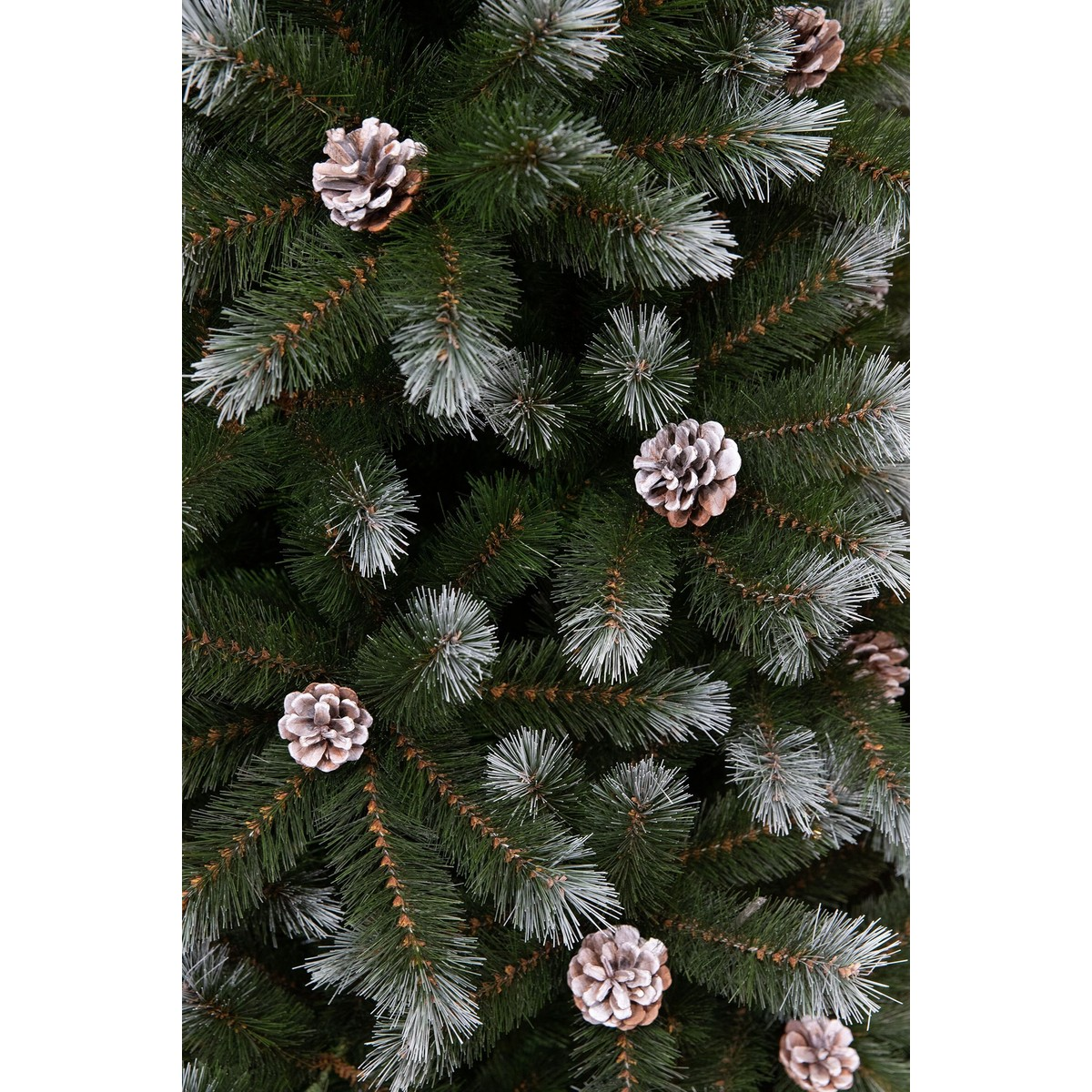 Close-up of an artificial Christmas tree with green, white-tipped branches and small pinecones.