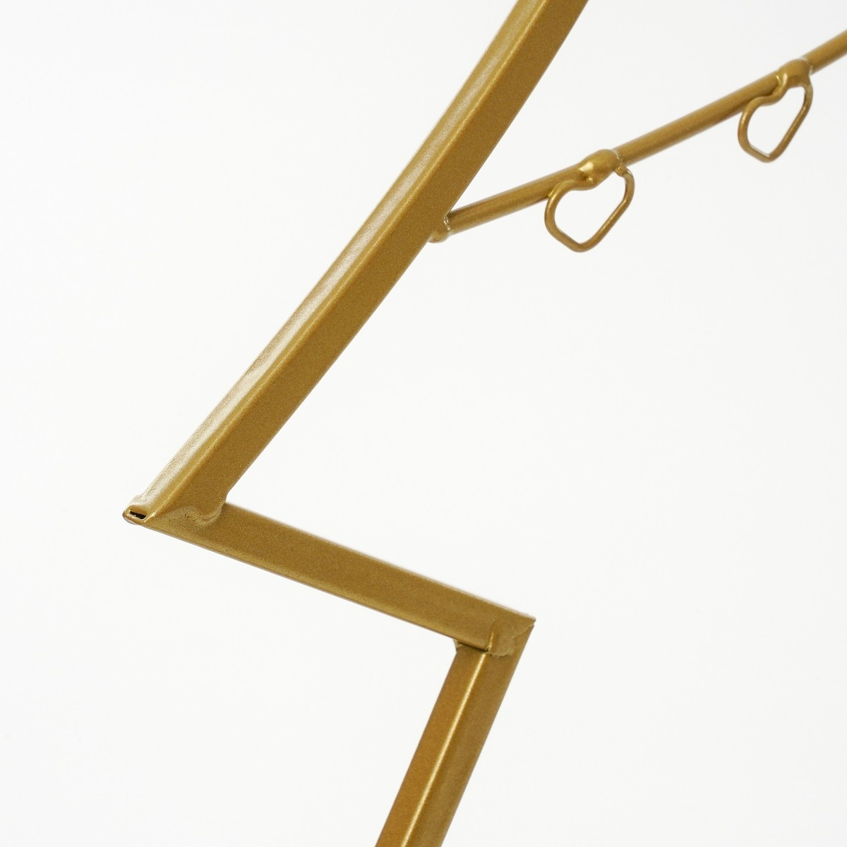 Gold-colored metal structure with two small hearts on a rod against a white background.