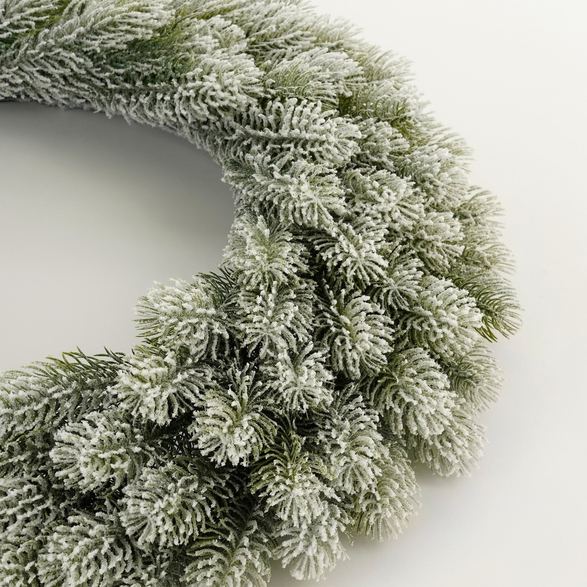 A frosted green Christmas wreath on a plain white background.