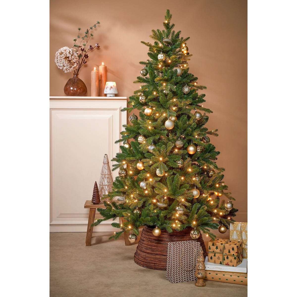 A decorated Christmas tree with golden ornaments and lights stands in a cozy room with gift boxes.