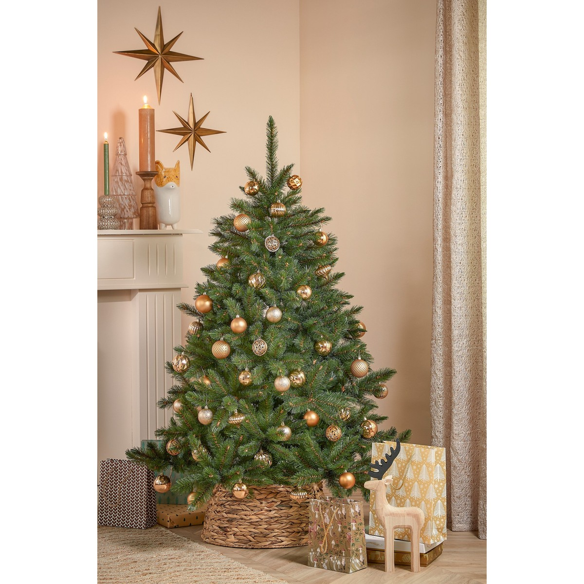 A decorated Christmas tree with gold ornaments stands in a room, flanked by gift bags and a fireplace.
