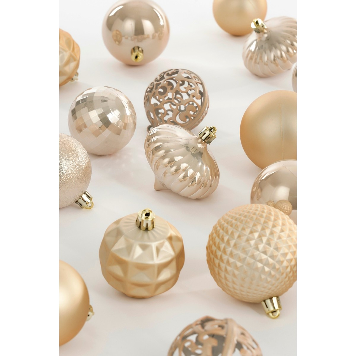 Various gold and rose gold Christmas ornaments with shiny, matte, and patterned textures on a white surface.
