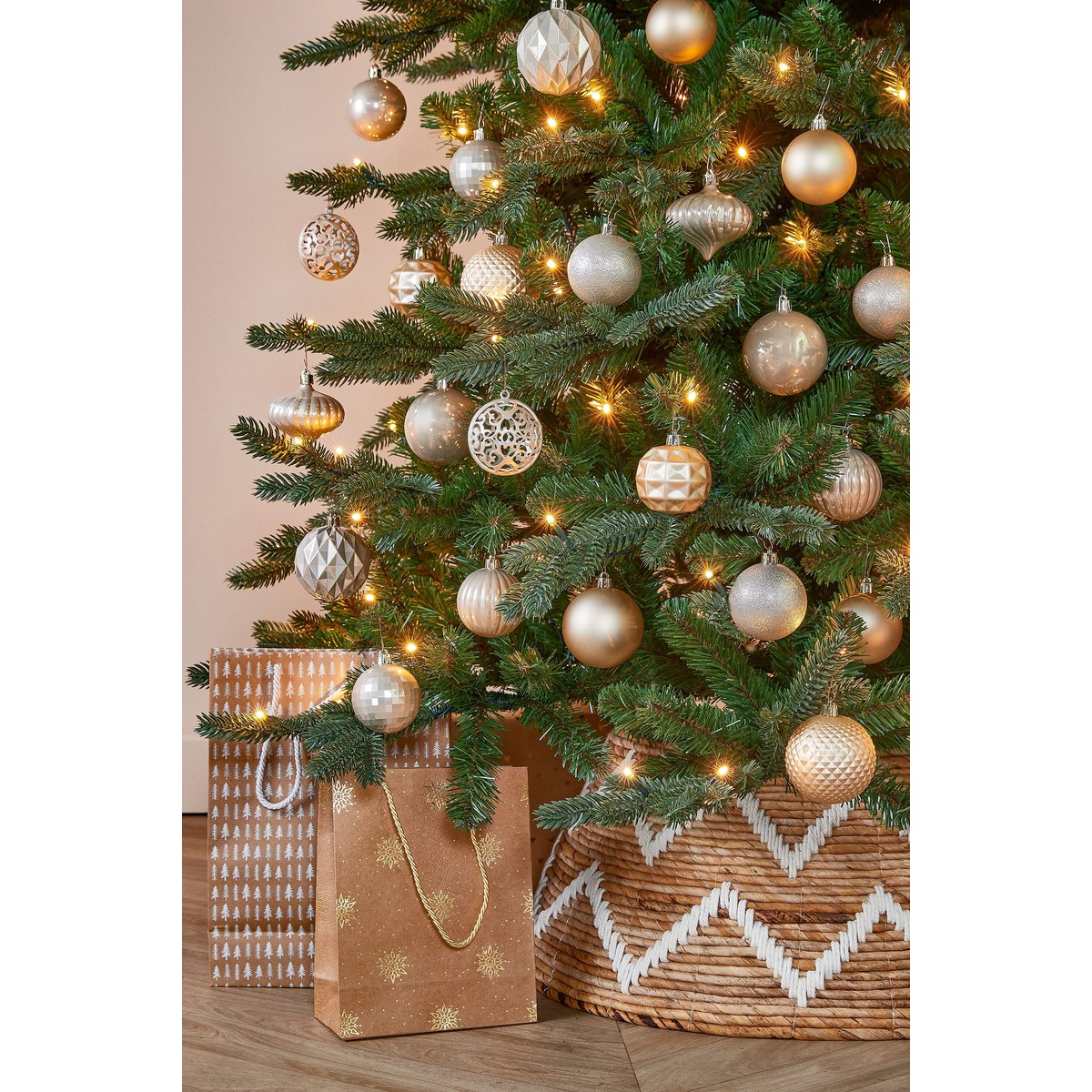 A decorated Christmas tree with gold and silver baubles, lights, and gift bags underneath.