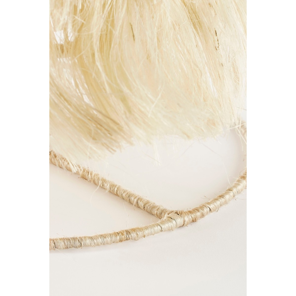 Close-up of a beige fringed lamp with a textured wire structure.