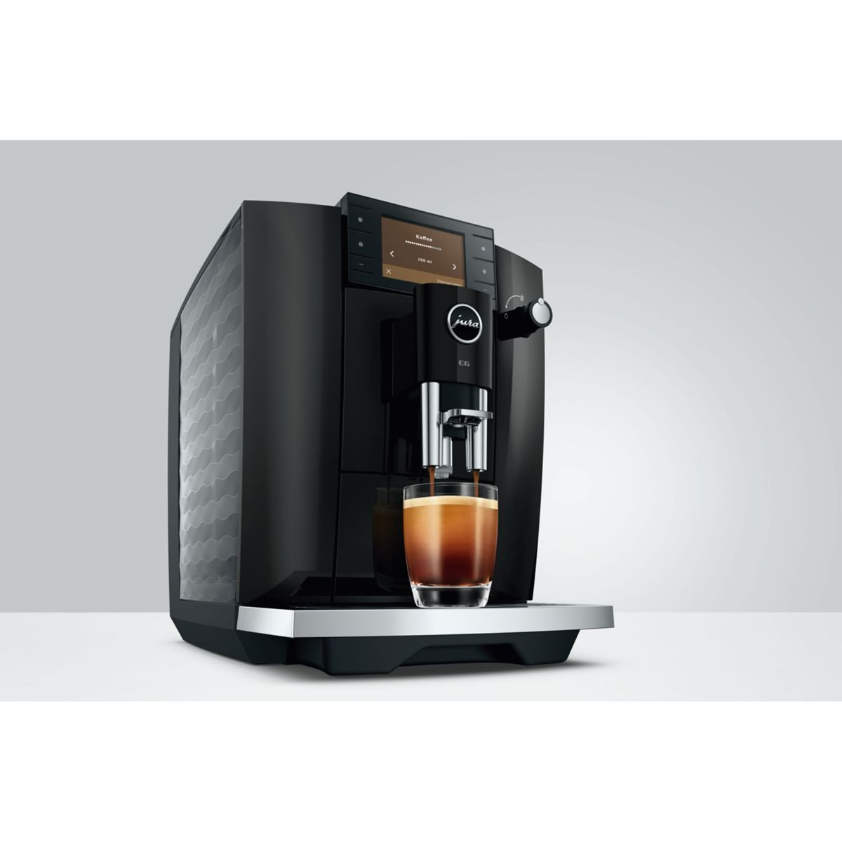 Macchina da caffè nera Jura E6 su sfondo bianco che versa espresso in un bicchiere.