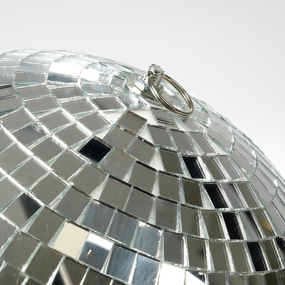 Gros plan d'une boule à facettes miroitée avec un anneau de suspension sur fond blanc.