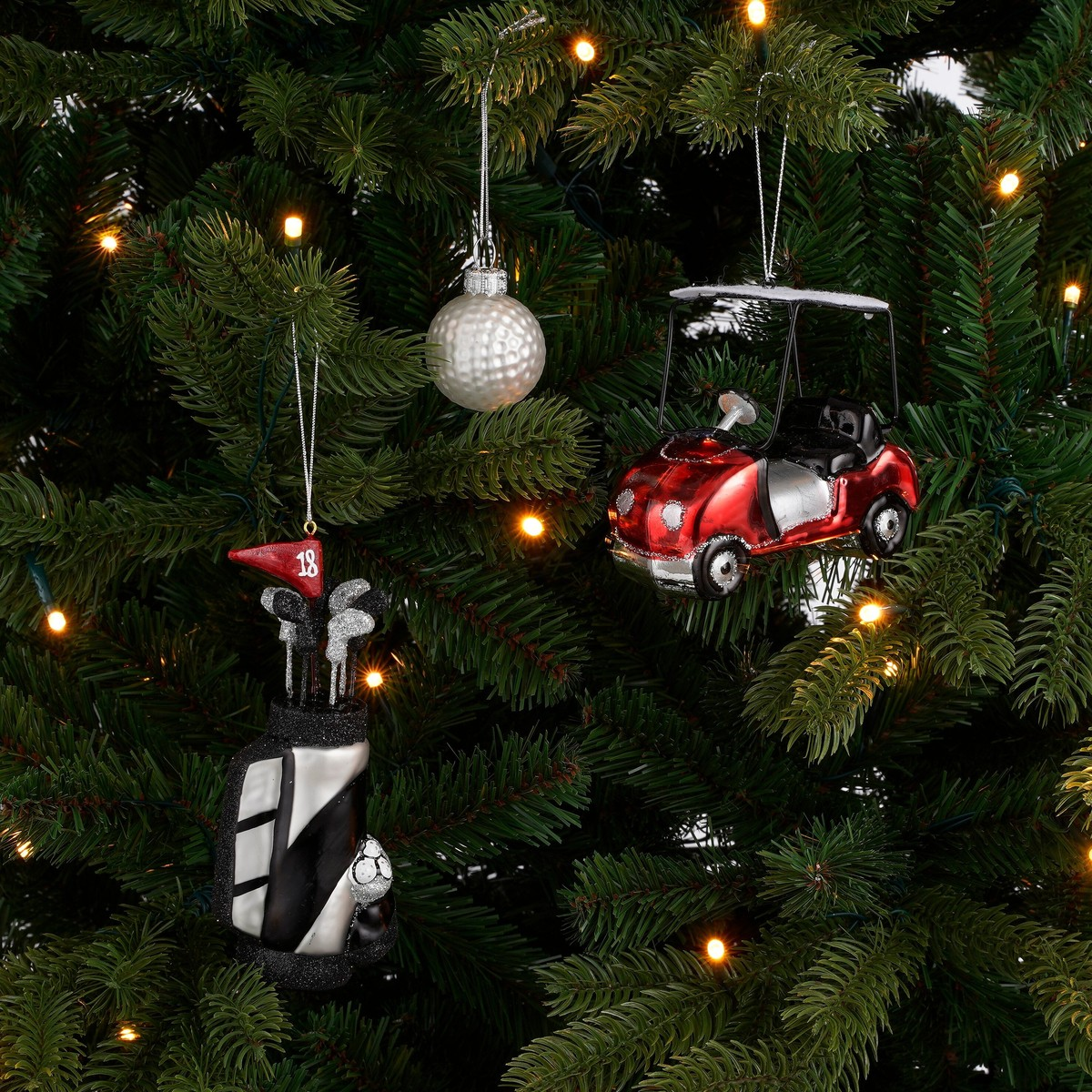 Golf-themed Christmas ornaments, including a golf bag, ball, and cart, hanging on a tree.