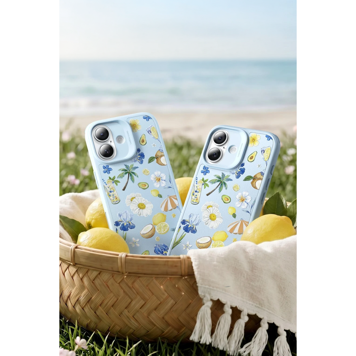 Yaz desenli iki açık mavi telefon kılıfı, limonlu sepet içinde ve plaj arka planında.