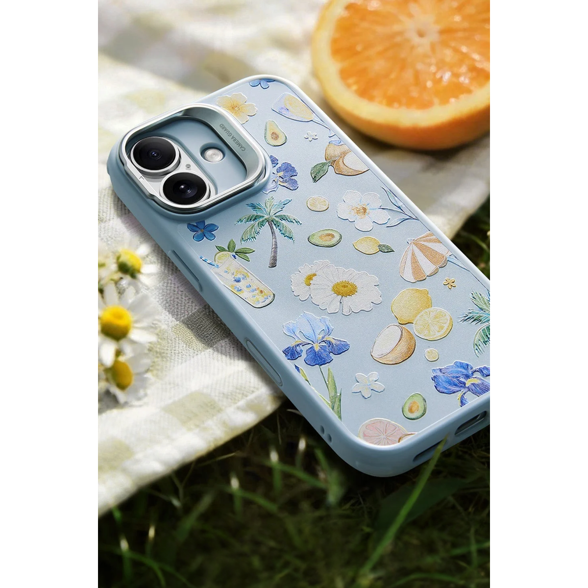 Yaz motifli mavi telefon kılıfı, bir portakalın yanında örtü üzerinde duruyor.