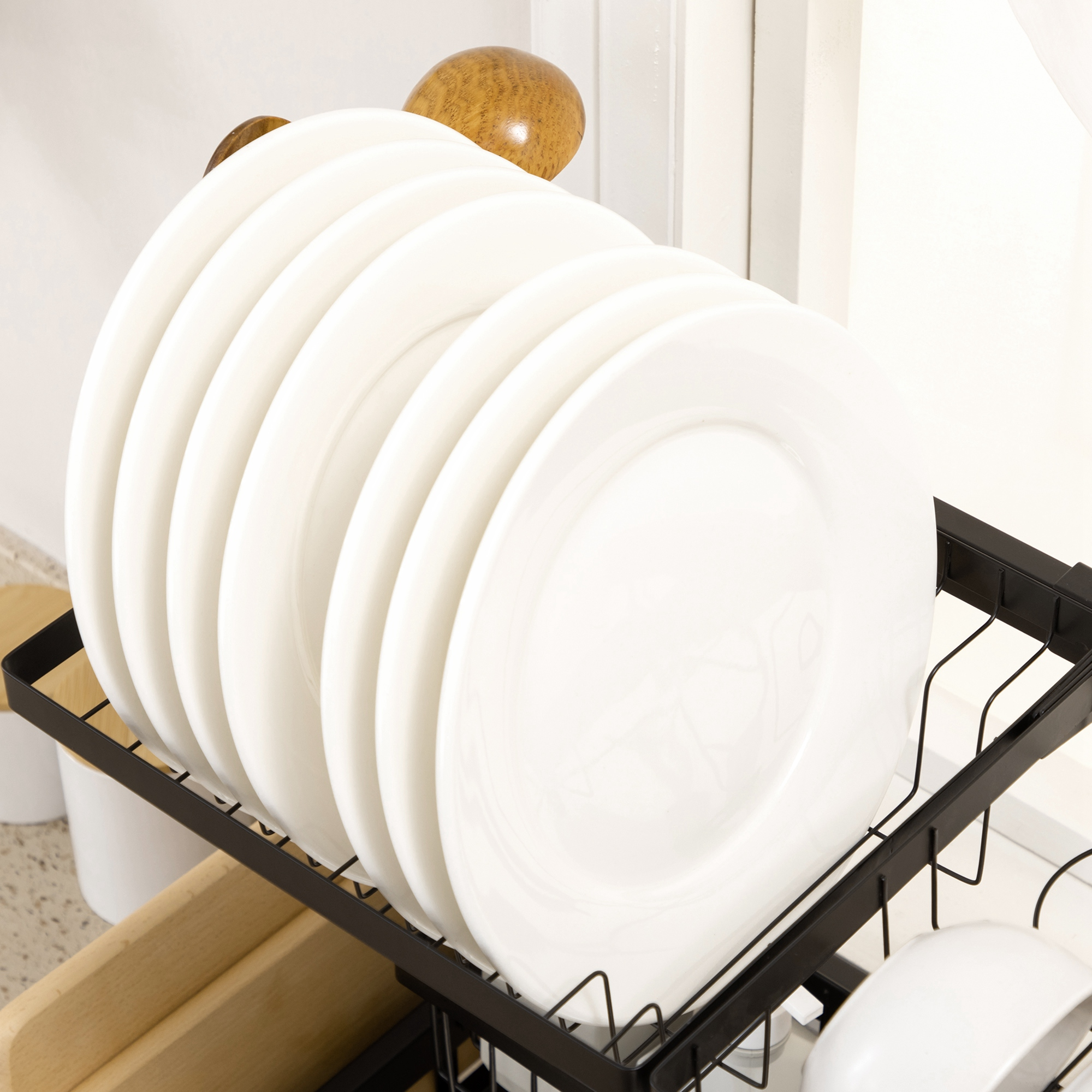Platos blancos en un estante negro, con una cocina luminosa al fondo.