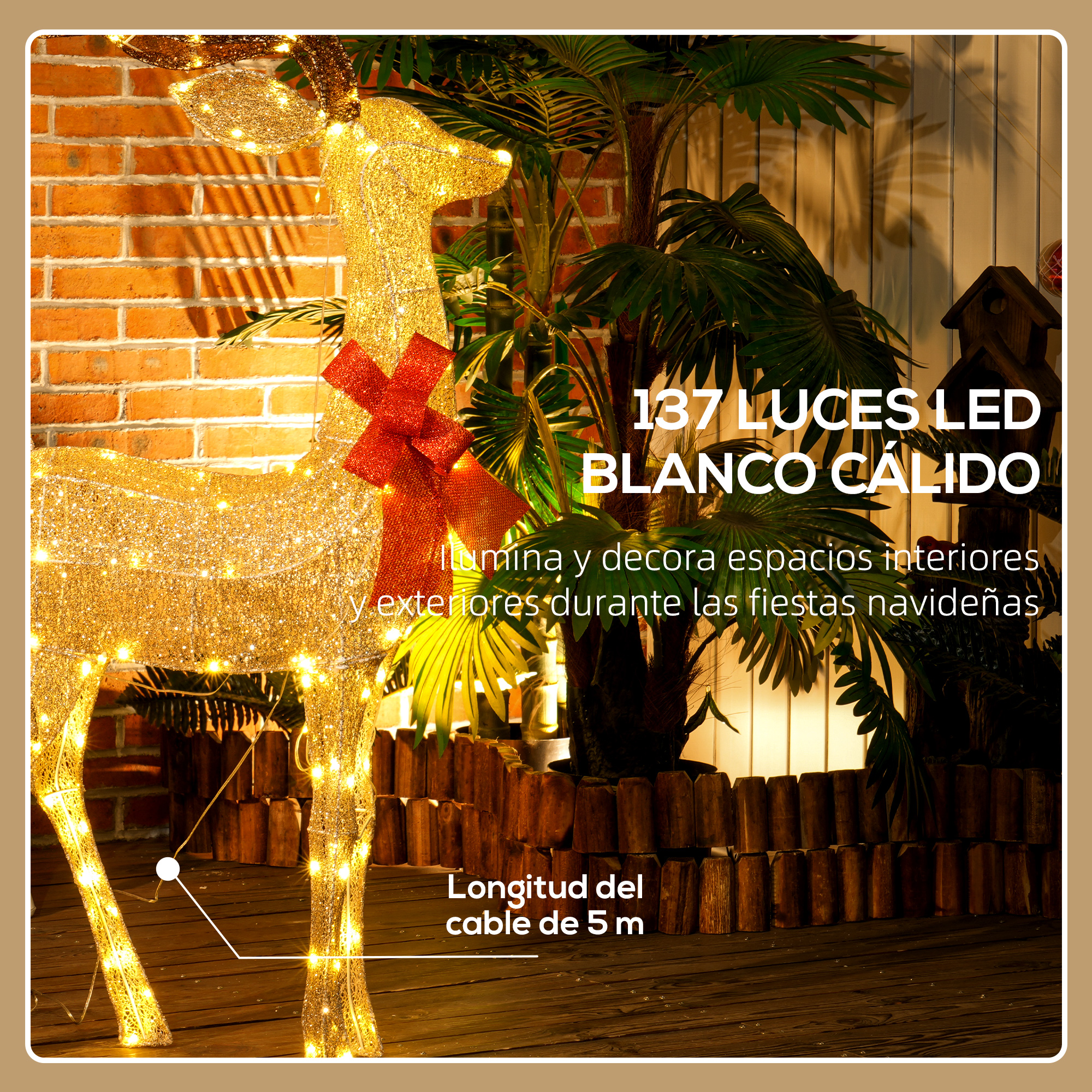 Un reno decorativo dorado iluminado con un lazo rojo se encuentra ante una pared de ladrillo y plantas.
