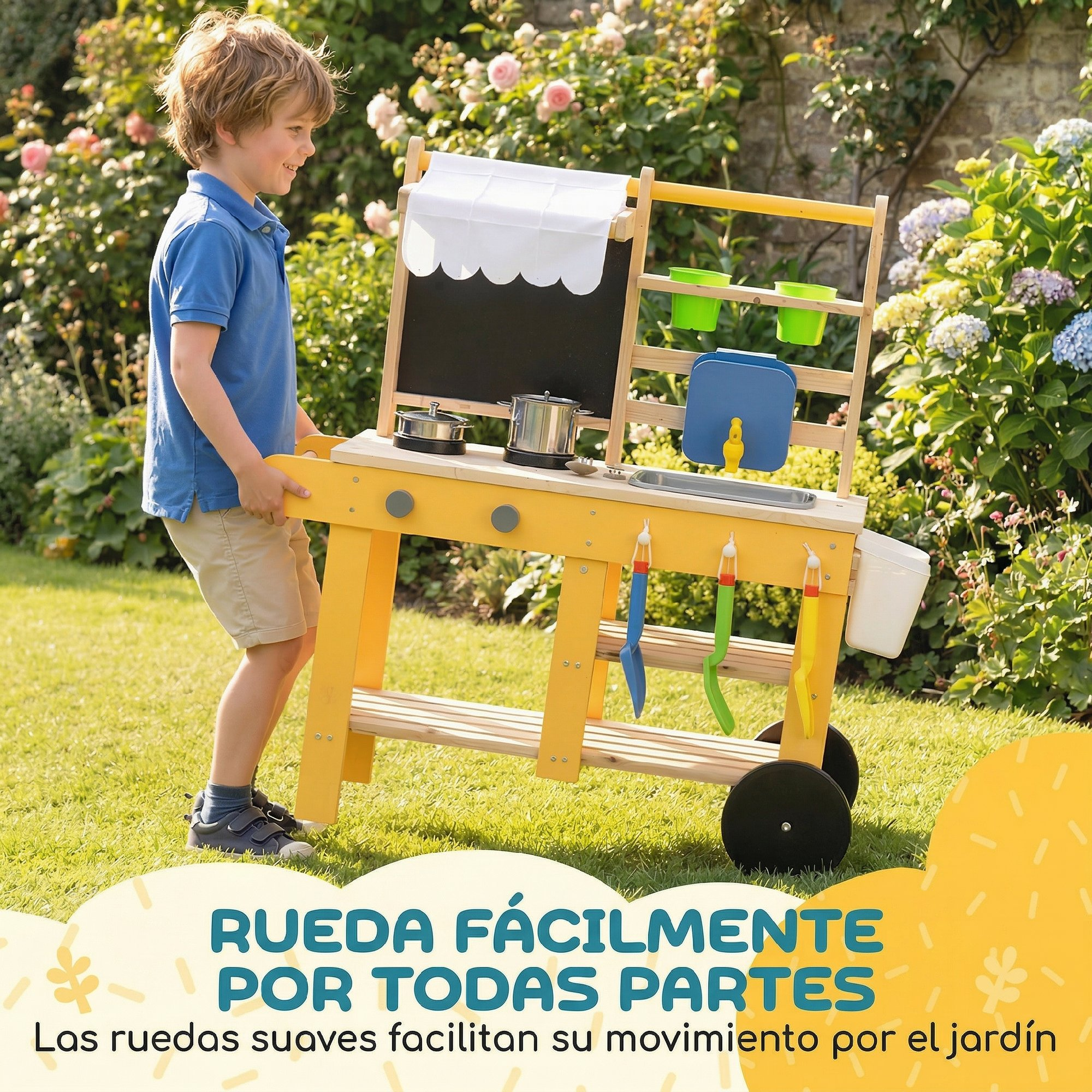 Un niño empuja una cocina de juguete de madera con ruedas en un jardín.