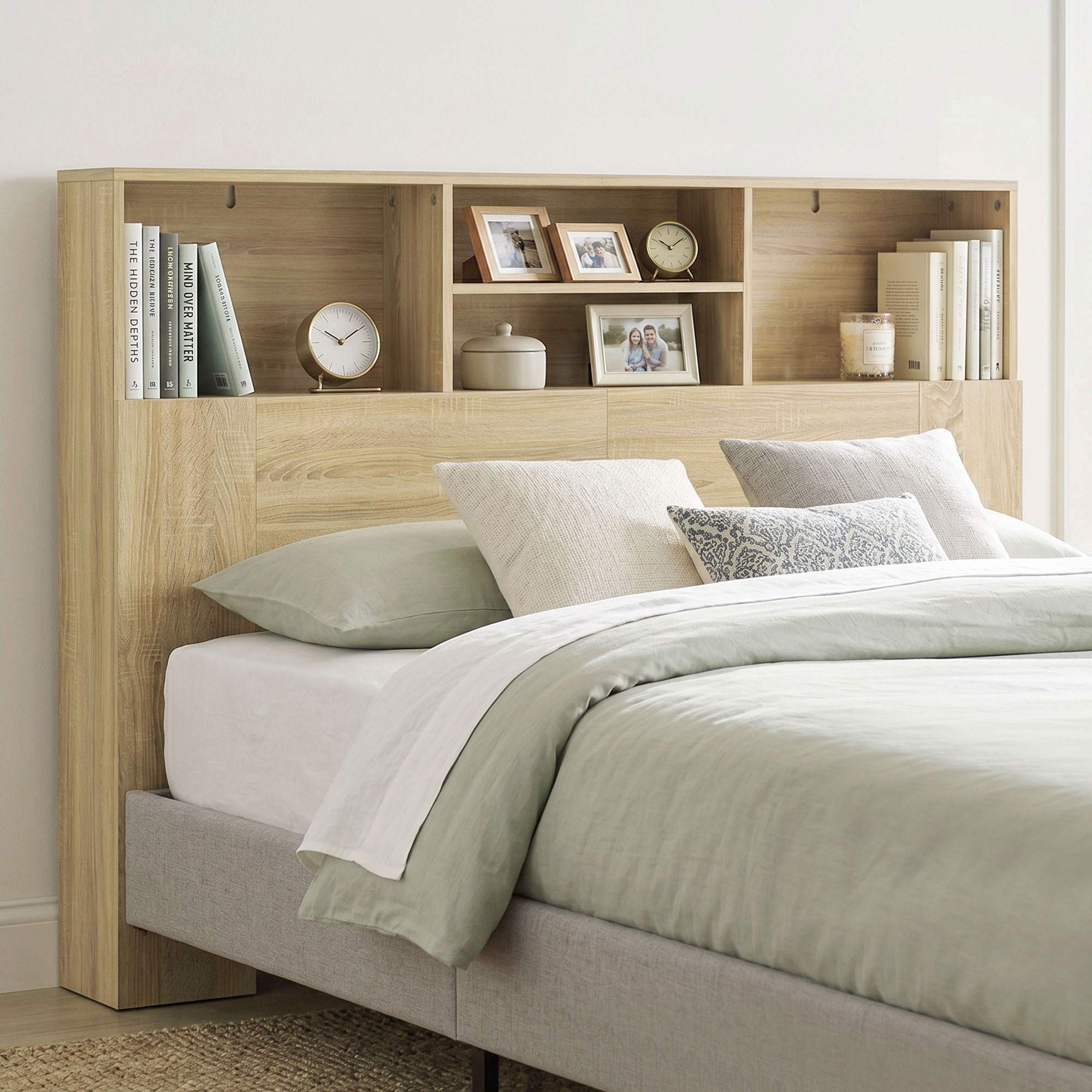 Una cama con cabecero de madera clara y estantes con libros, fotos y relojes.
