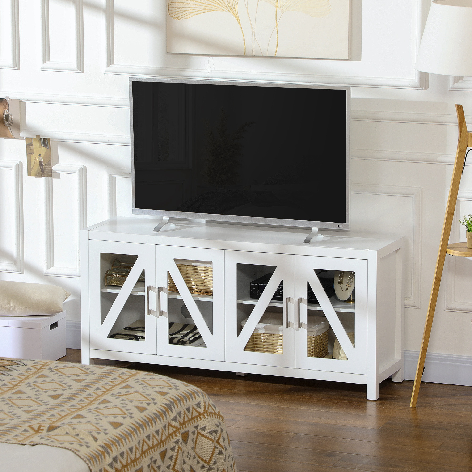 Un mueble de TV blanco con puertas de cristal está en una habitación luminosa, soportando un gran televisor.