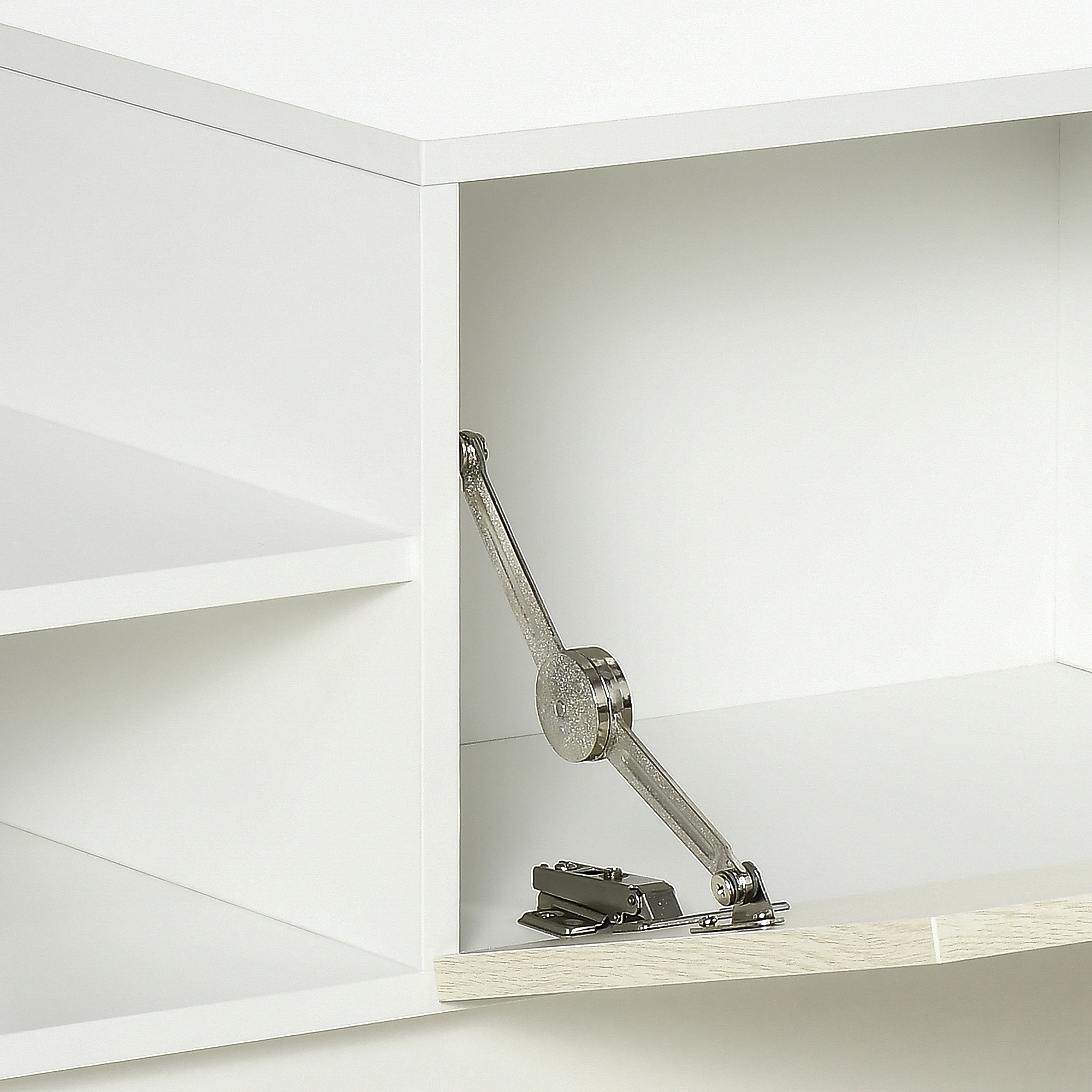 Primer plano de un mecanismo de bisagra metálica plateada unido a una puerta de gabinete de madera blanca.