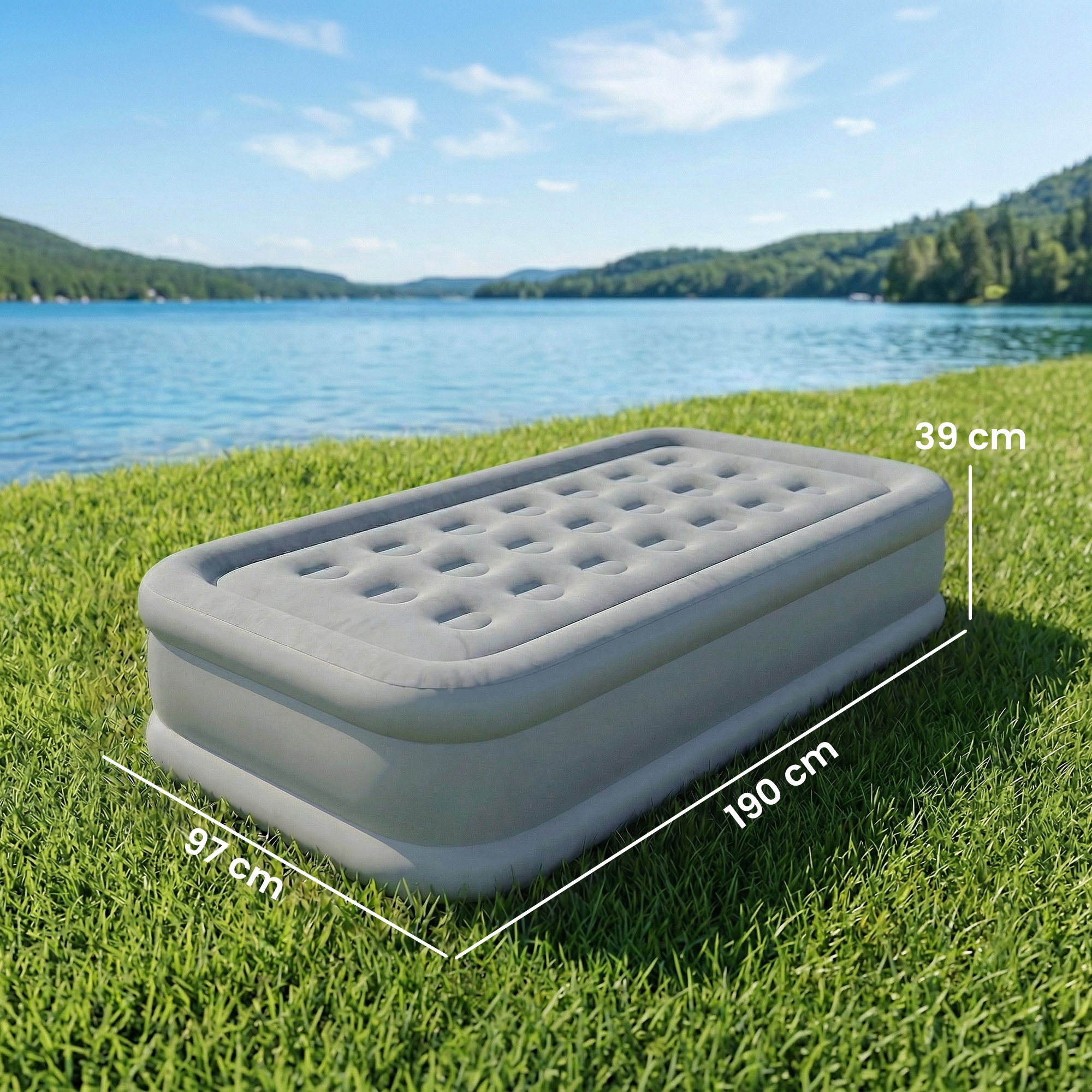 Un colchón inflable gris sobre hierba verde junto a un lago con medidas.