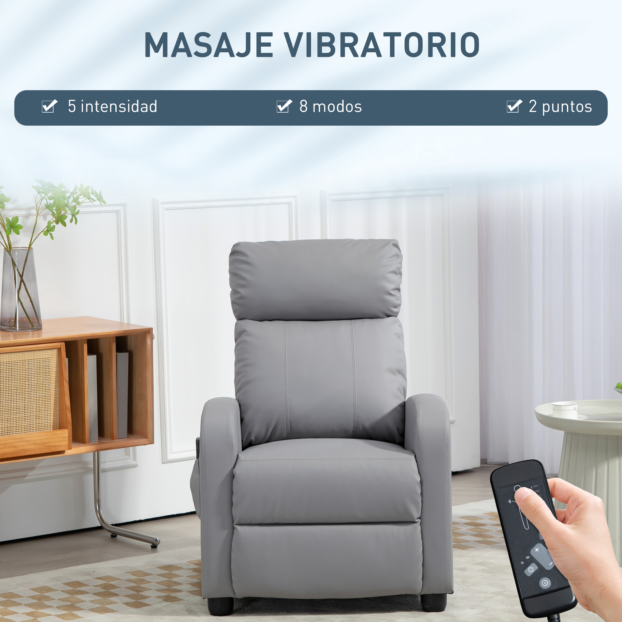 Un sillón de masaje gris con una mano sosteniendo un control remoto, junto a un mueble.