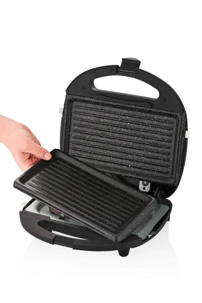 Bir el, açık tost makinesinden siyah bir ızgara plakası çıkarıyor.