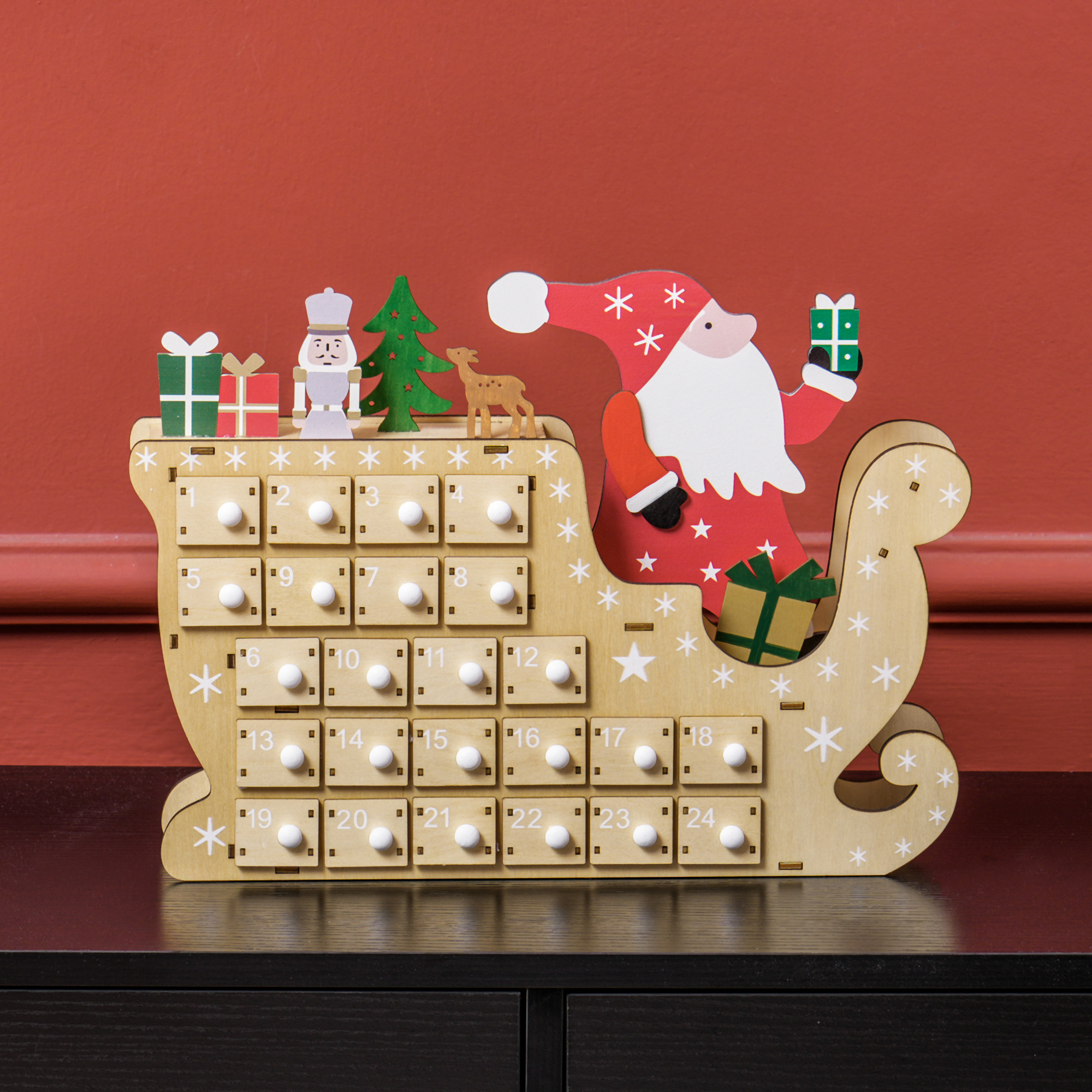 Un calendario de Adviento navideño de madera con forma de trineo con 24 cajones numerados, Papá Noel y regalos.