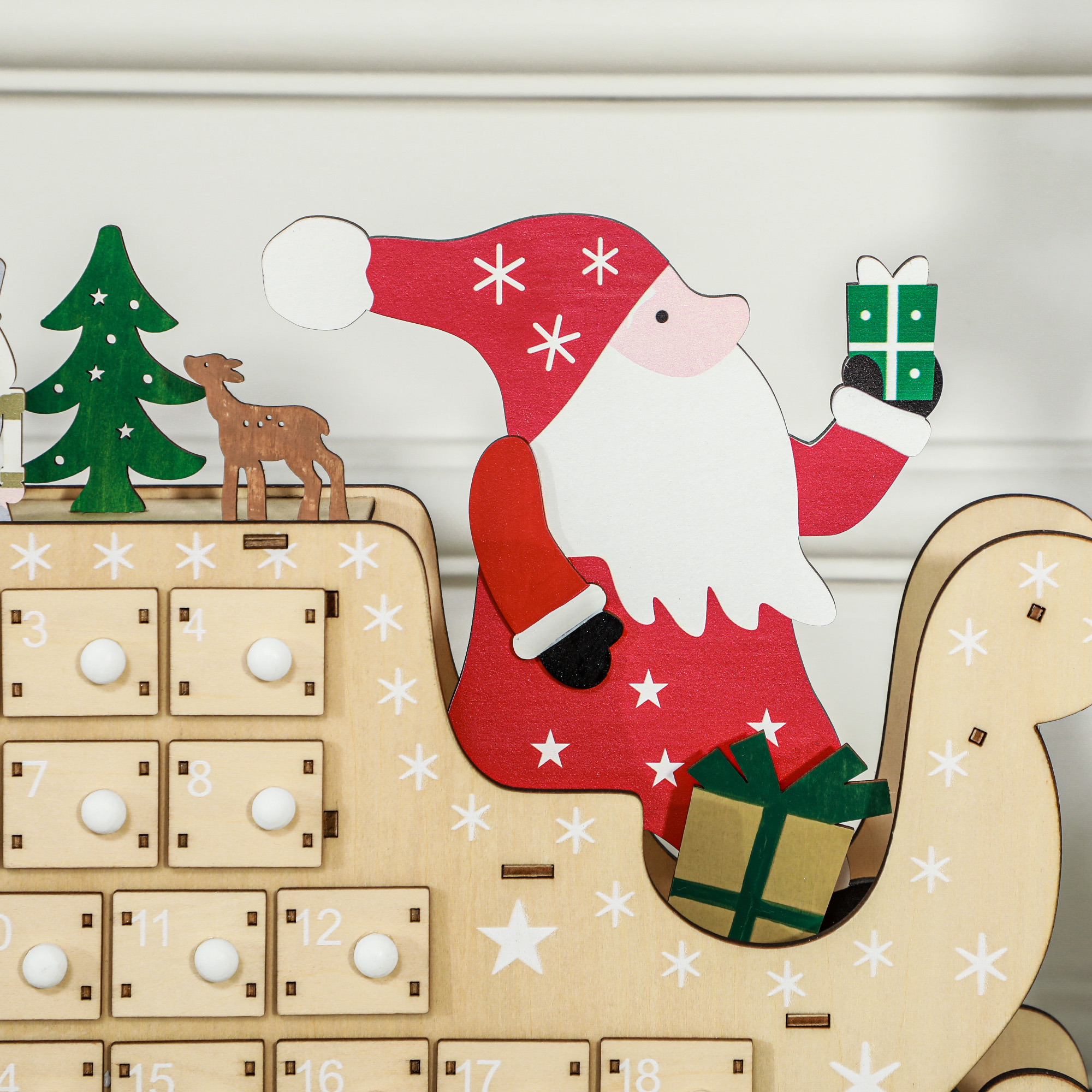 Un calendario de adviento de madera en forma de trineo con Papá Noel, regalos, un árbol de Navidad y un reno.
