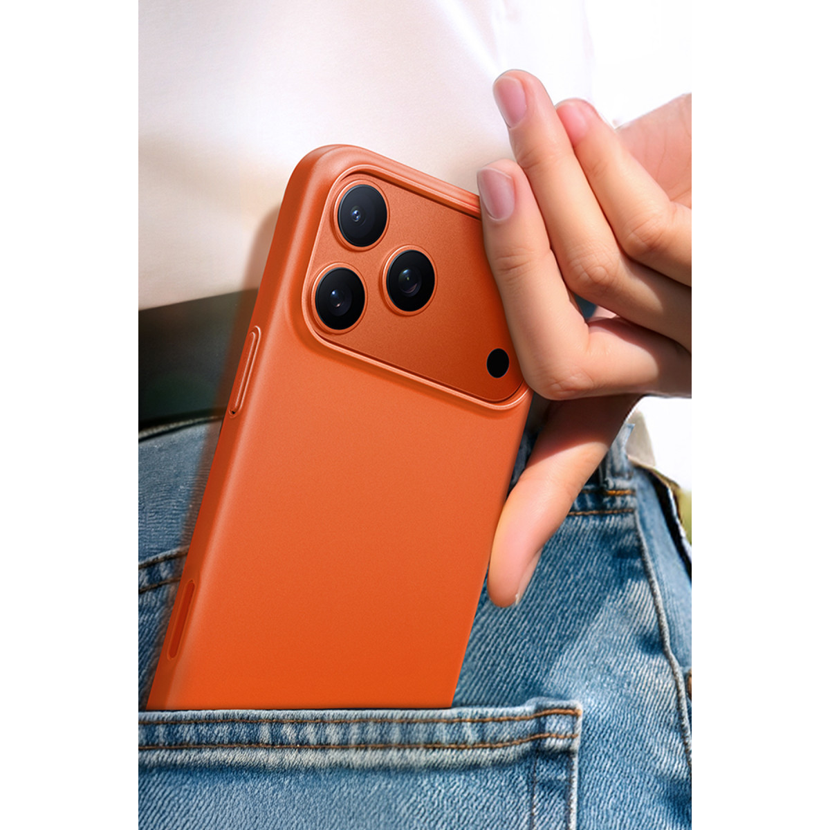 Üç kameralı turuncu akıllı telefonu kot cebine koyan bir el.