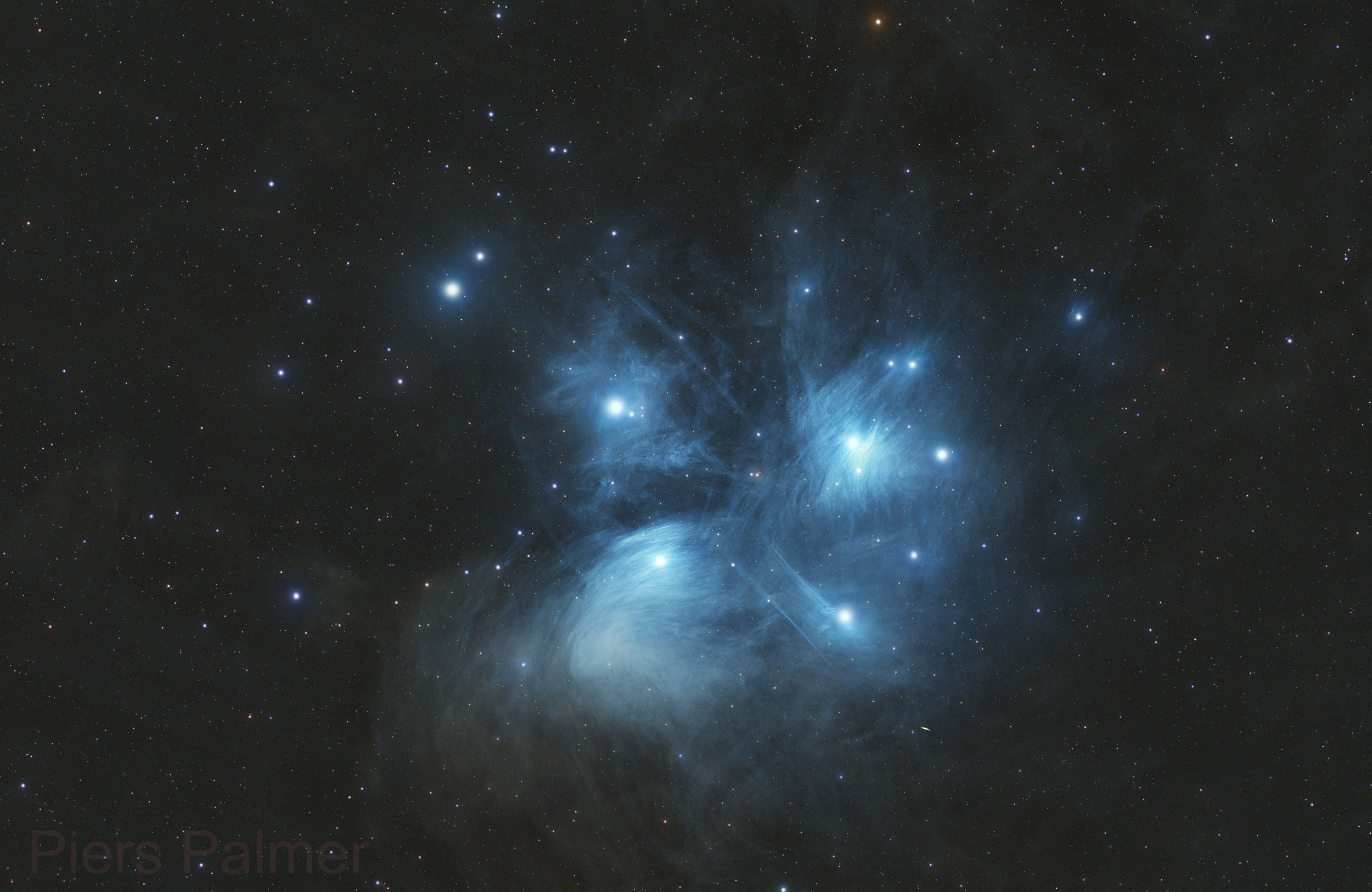El cúmulo estelar de las Pléyades brilla en azul brillante en medio del espacio estelar oscuro.