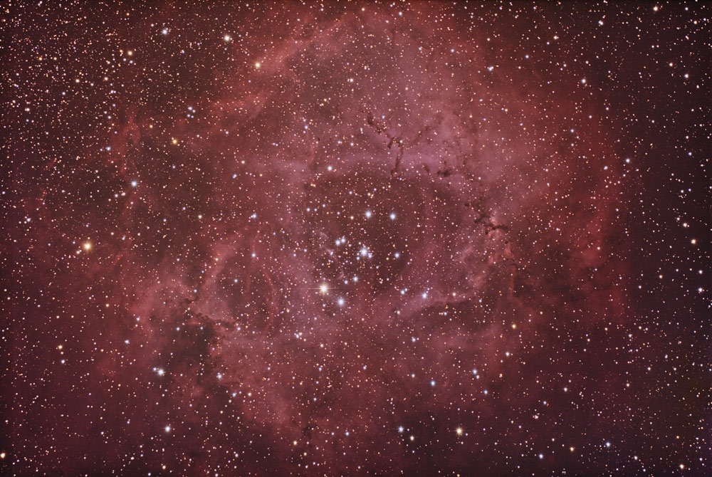 Una vasta nebulosa cósmica rojiza llena de innumerables estrellas brillantes en el espacio.