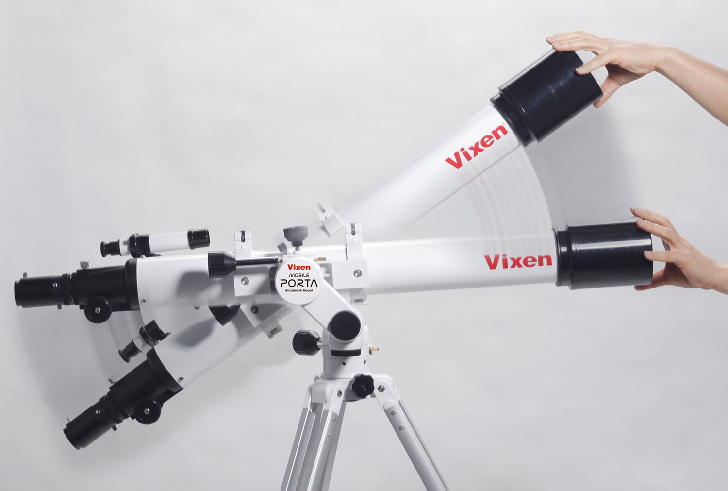 Un telescopio blanco Vixen en un trípode muestra movimiento mientras las manos ajustan su ángulo.