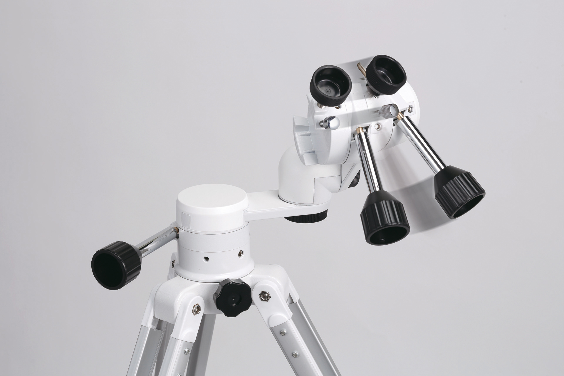 Una montura de telescopio astronómico blanca con patas plateadas y perillas de ajuste negras sobre fondo gris.