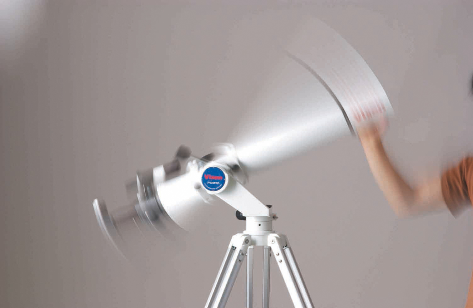 Una imagen borrosa de un telescopio blanco en un trípode, movido por una persona.
