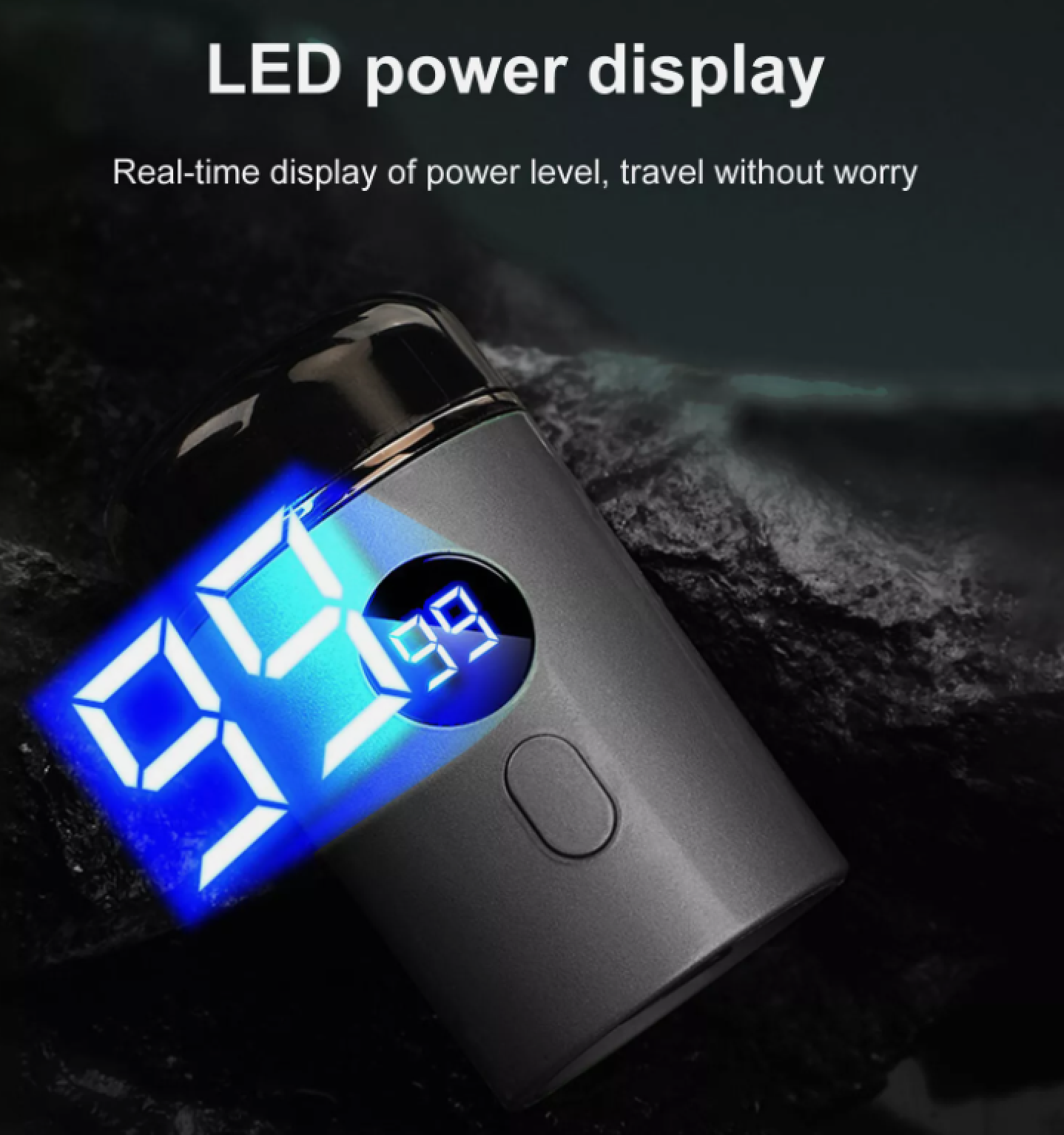 Ein grauer elektrischer Rasierer mit einer blauen LED-Anzeige zeigt den Akkustand auf einem dunklen Felsen.