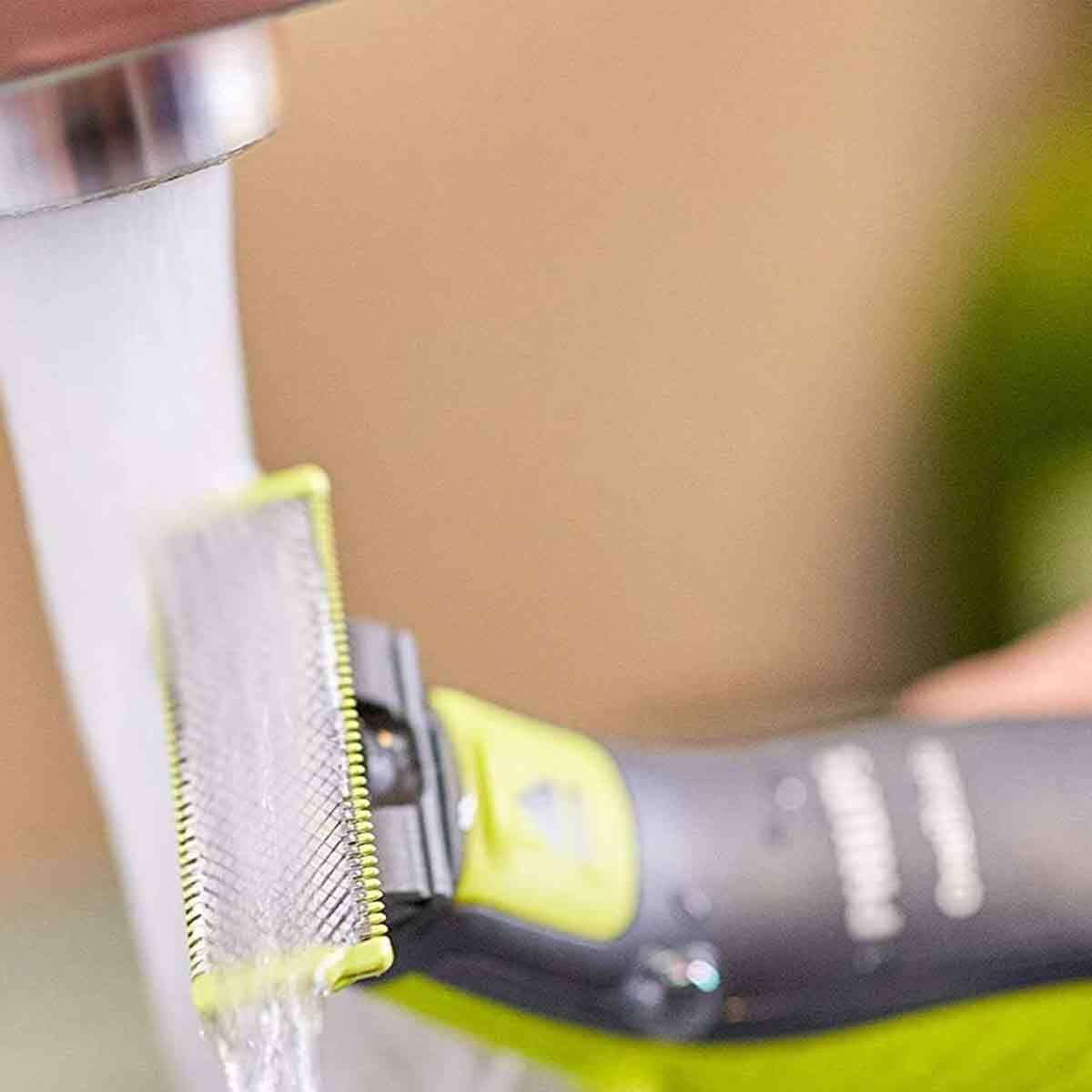 Ein elektrischer Rasierer wird unter fließendem Wasser gereinigt.