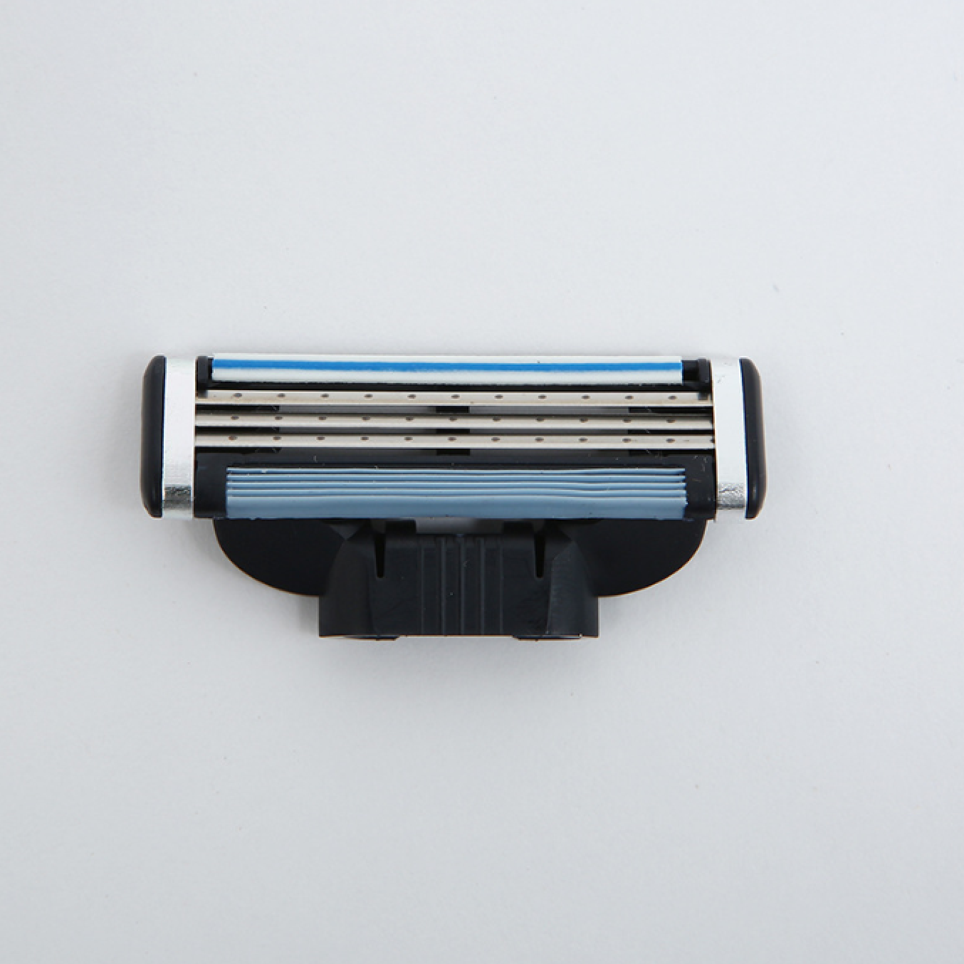 Nahaufnahme einer Mehrklingen-Rasierkassette mit silbernen Klingen, einem blauen Streifen und schwarzem Sockel auf weißem Grund.