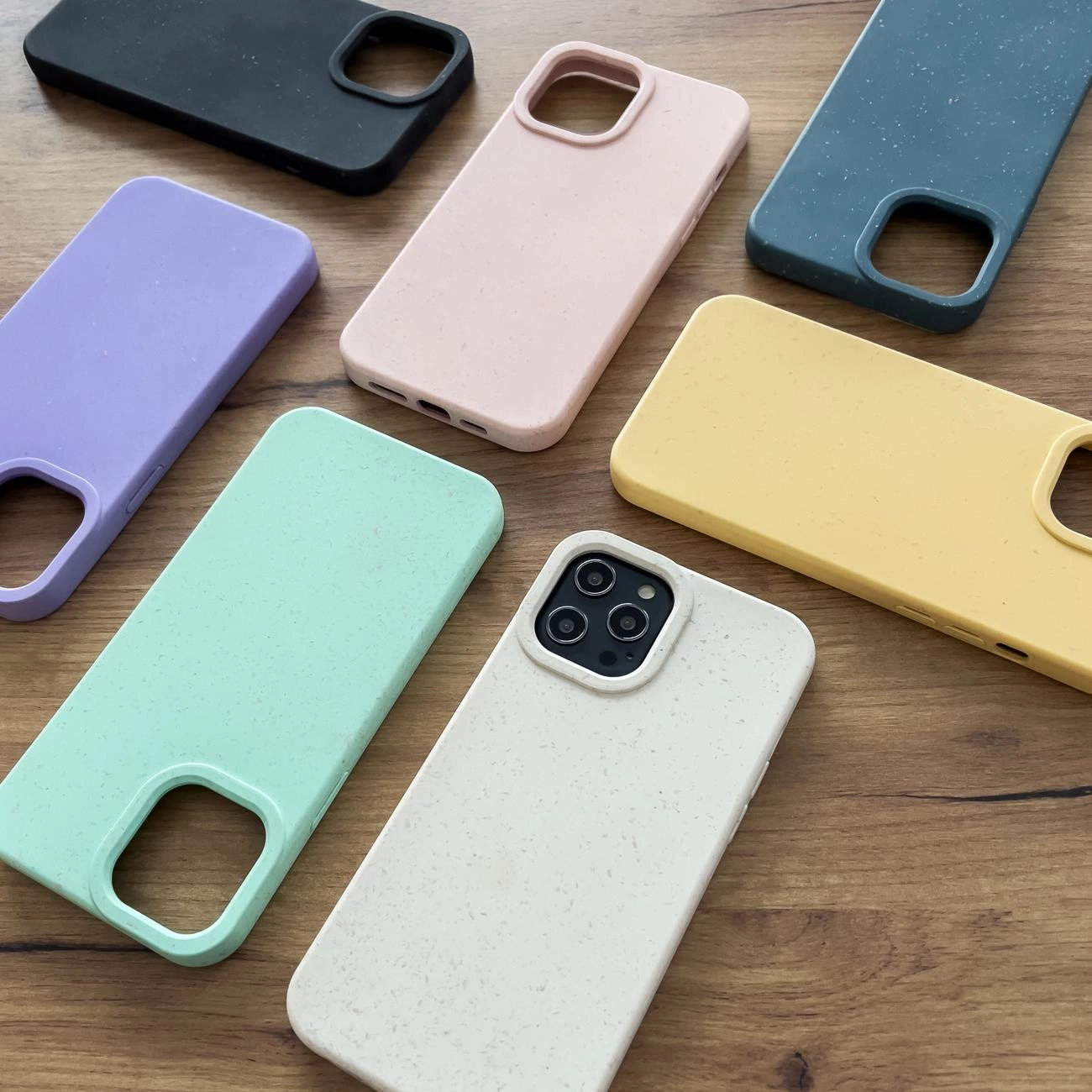Diverse custodie per smartphone colorate e opache disposte su una superficie di legno.
