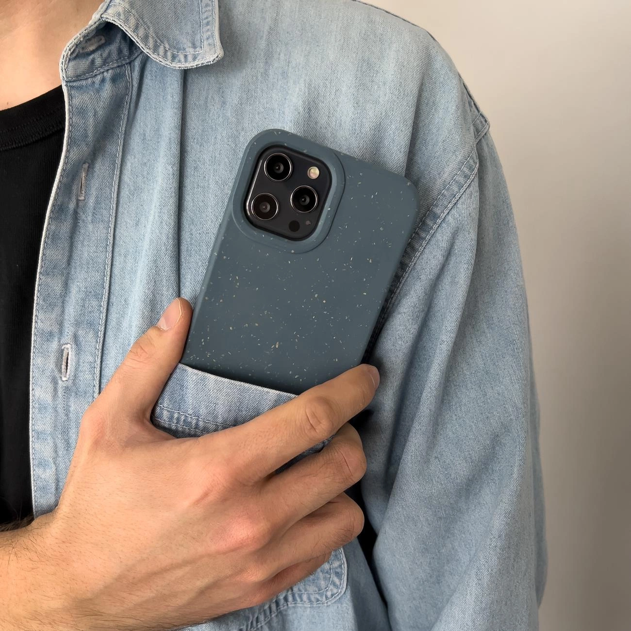 Uno smartphone in custodia blu maculata è nel taschino di una camicia di jeans.