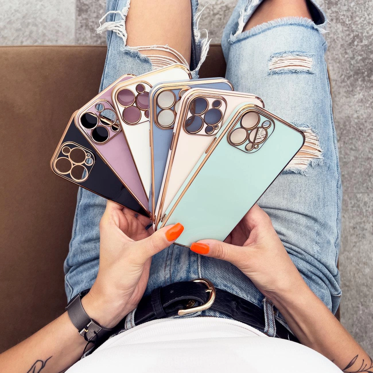 Una persona che tiene più smartphone in varie custodie pastello e neutre con dettagli della fotocamera in oro rosa.