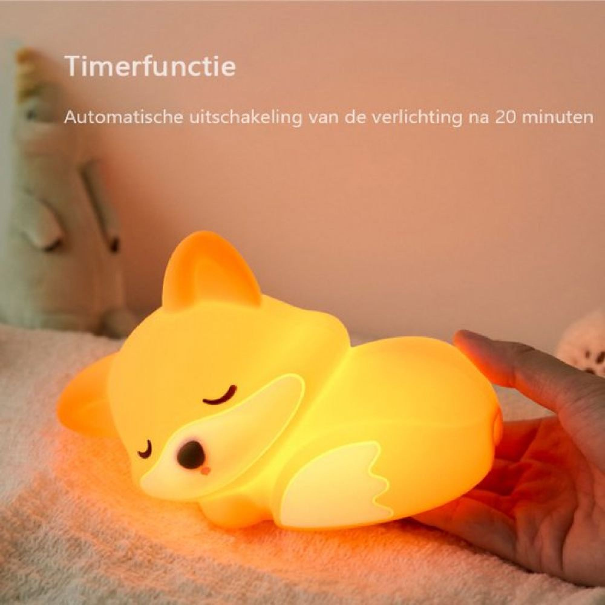 Eine Hand hält eine niedliche, leuchtende Fuchs-Nachtlampe auf weichem Untergrund.