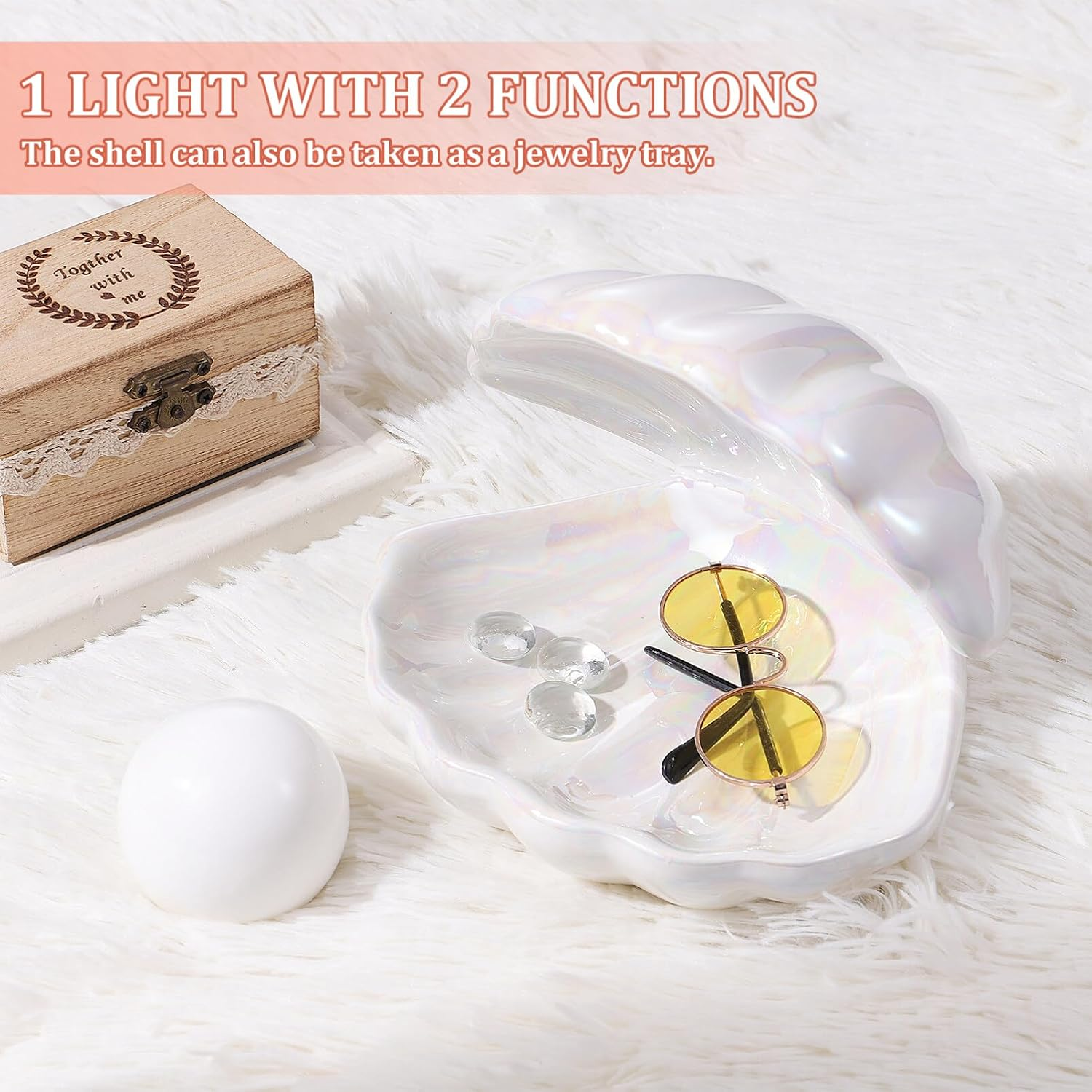 Eine perlmuttfarbene Muschelschale als Schmuckschale mit Sonnenbrille und Glasperlen auf weißem Fell.
