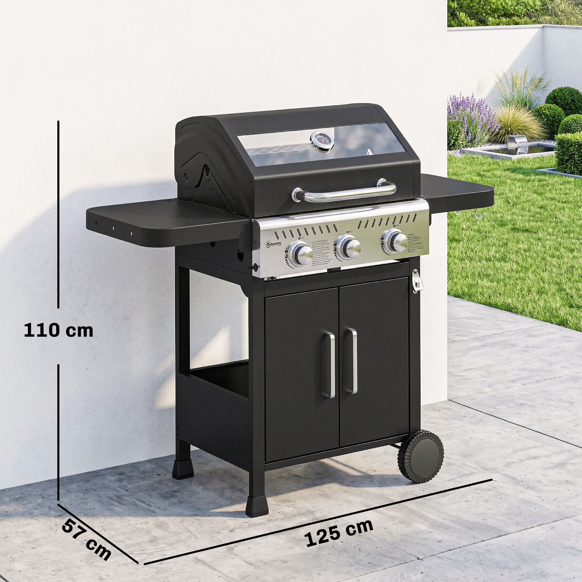 Barbacoa de gas negra con panel de acero inoxidable y estantes laterales en un patio frente a un muro con jardín.