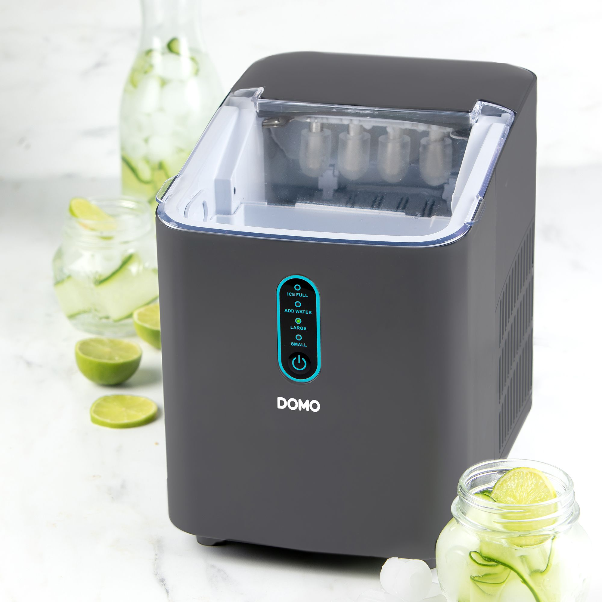 Eine graue DOMO Eismaschine auf weißer Marmorplatte mit Gläsern, Gurken und Limetten.